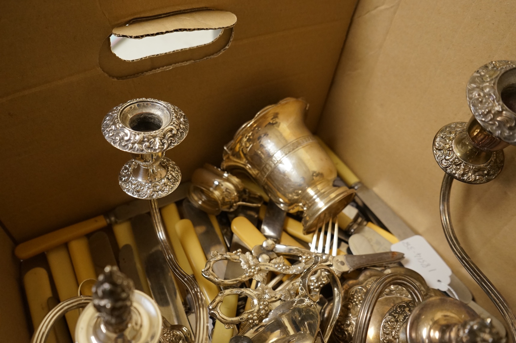A group of sundry plated items including dwarf candelabra, a pair of wine coasters, a pair of grape shears, etc., and a quantity of assorted ivorine handled table and dessert knives.